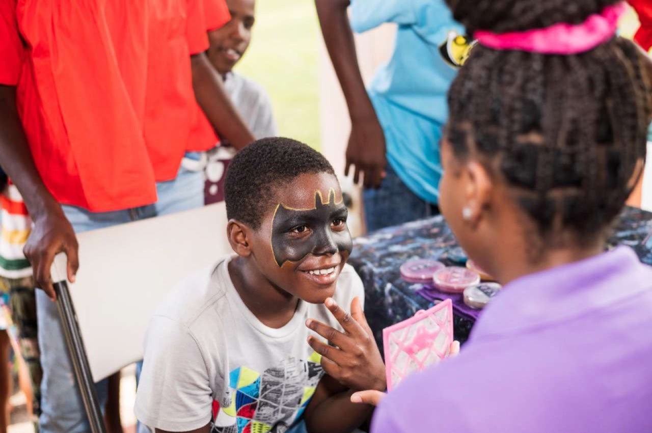 Boy with a painted face laughing with friends
