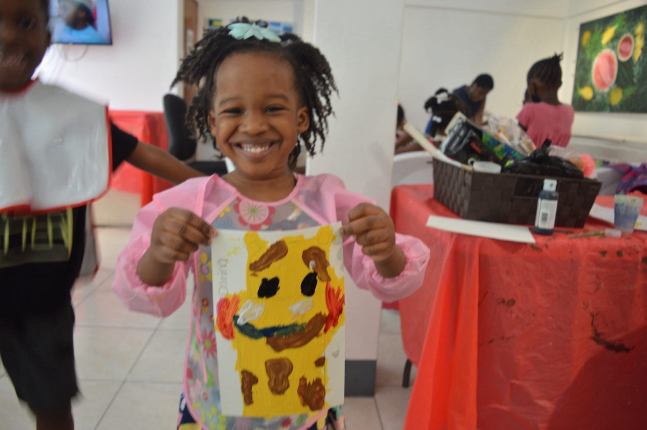 Girl proudly holding her giraffe painting